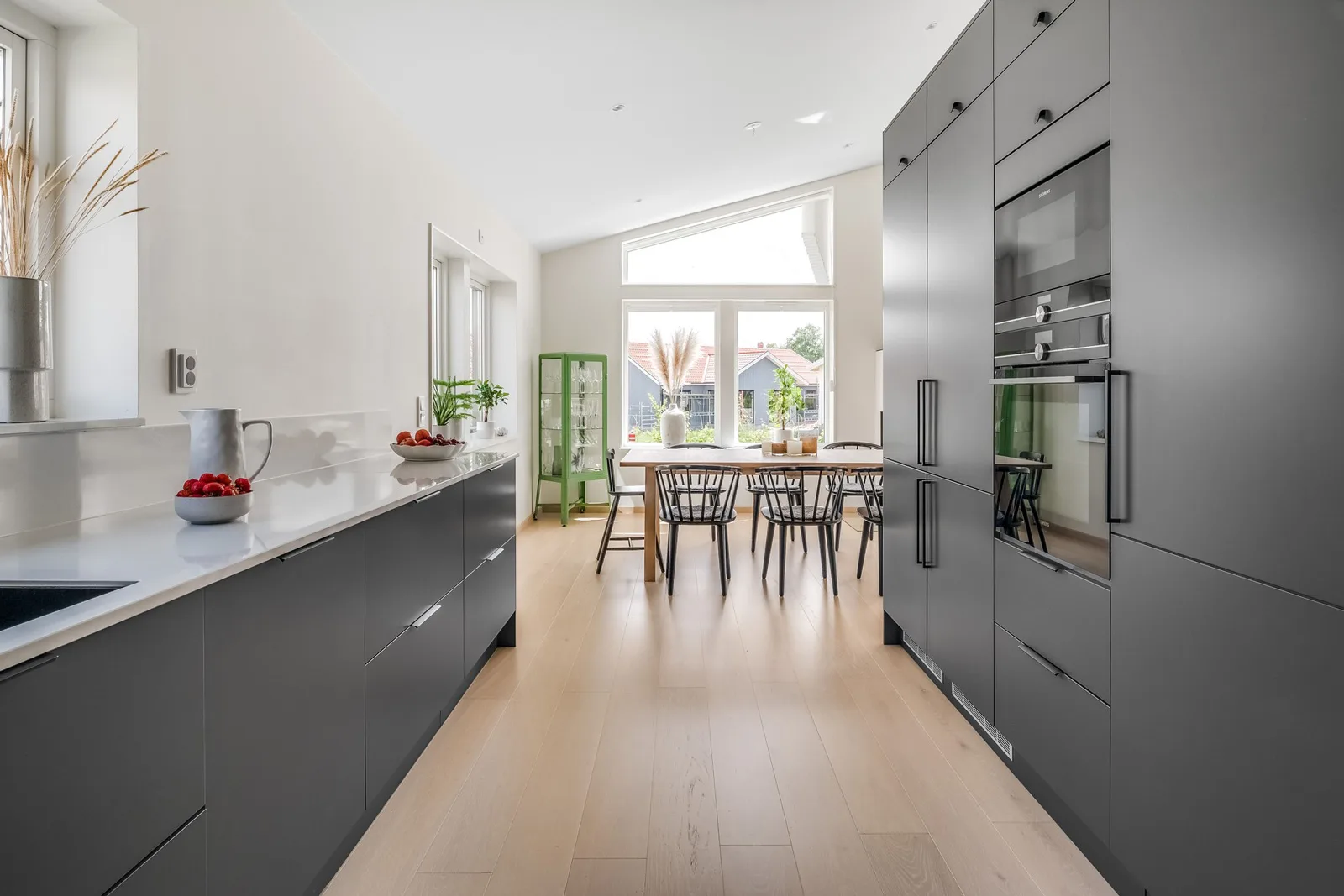 Kök med svarta köksluckor och matbord i Villa Stenskär.