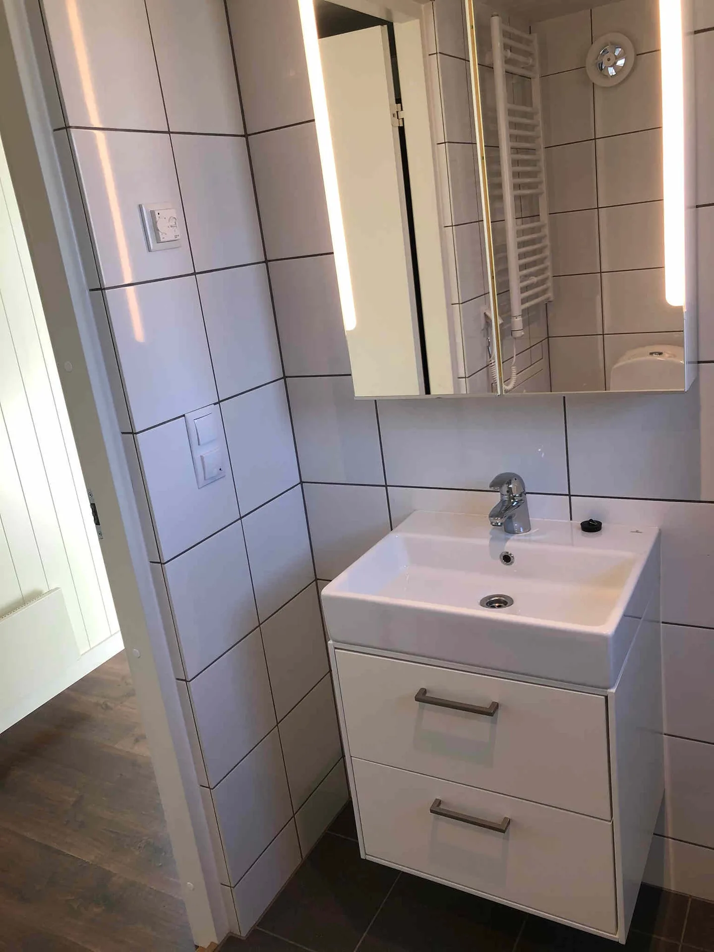 Badrum med plats för tvättmaskin, dusch, toalett, handfat och förvaring.