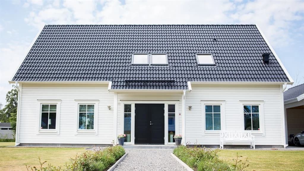 Exteriör bild av ett vitt kundunikt Varbergshus med svart pardörr