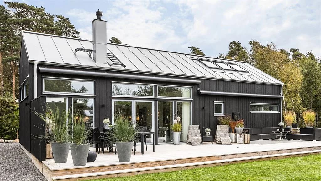Exteriör bild av ett svart kundunikt fritidshus från Varbergshus