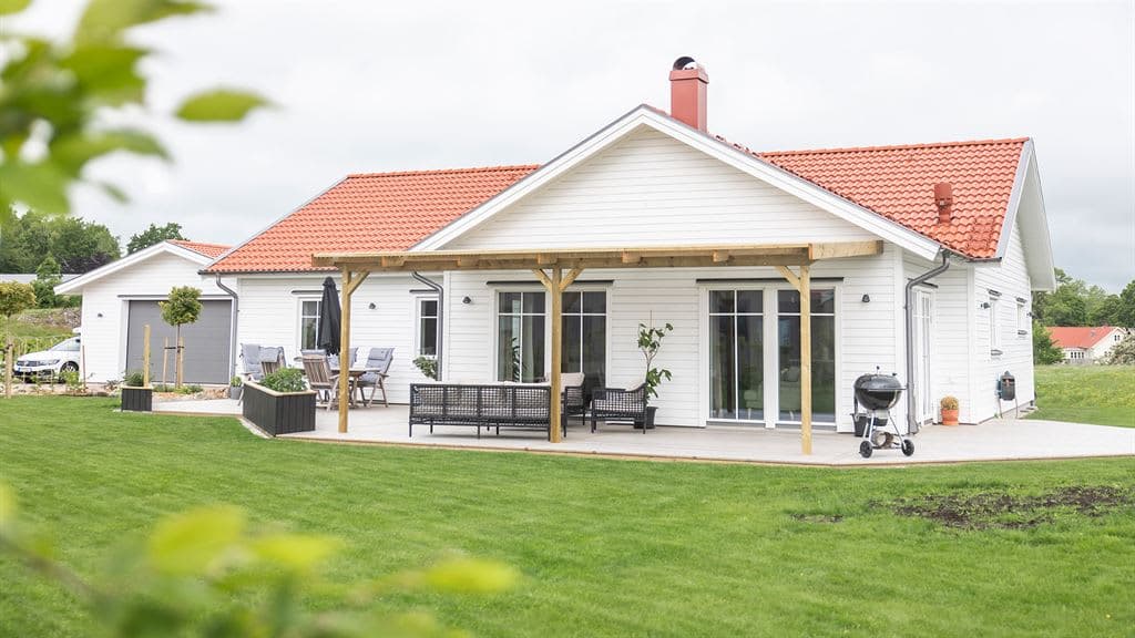Visualisering av vitt enplanshus och garage i lösvirke från Varbergshus