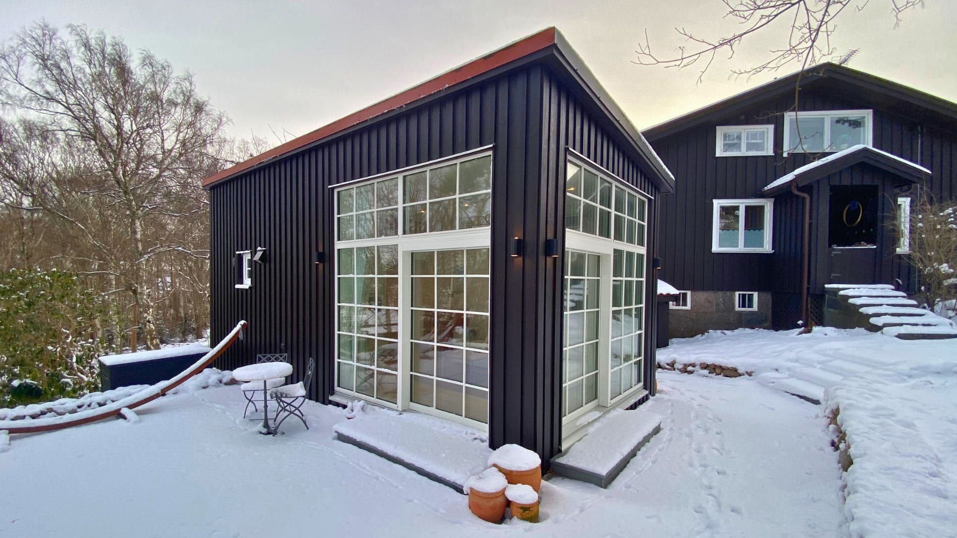 Svart attefallshus med stora fönster