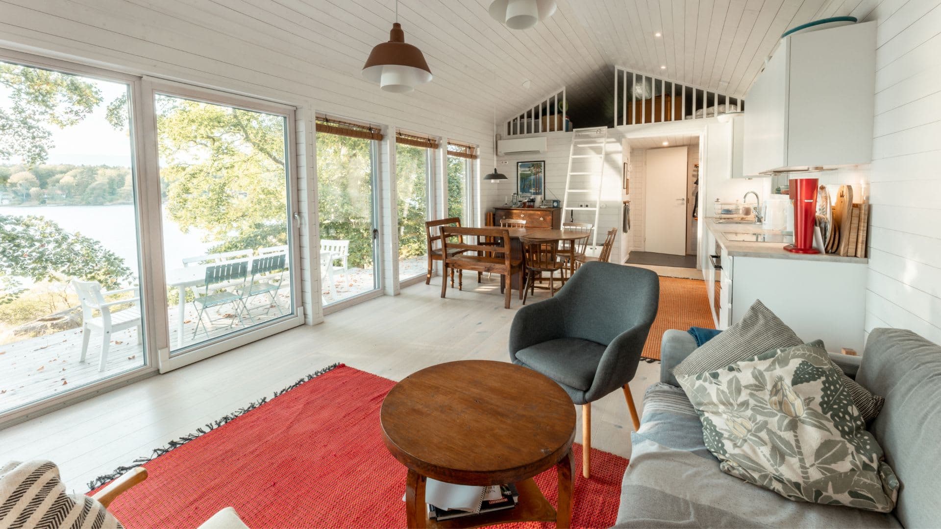 fritidshus vardagsrum med soffa, fåtölj och kök